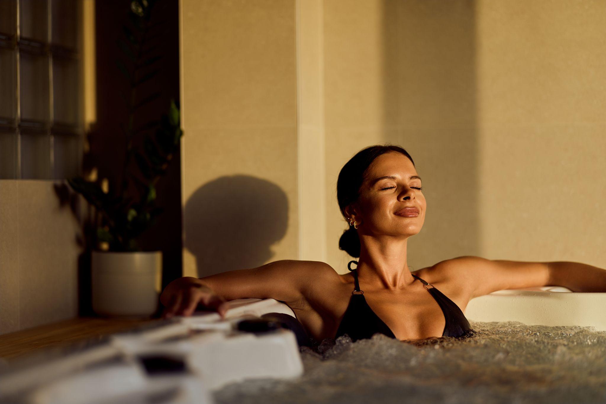 Person relaxing in a hot tub at home, enjoying a peaceful moment of wellness and stress relief in a private garden setting.